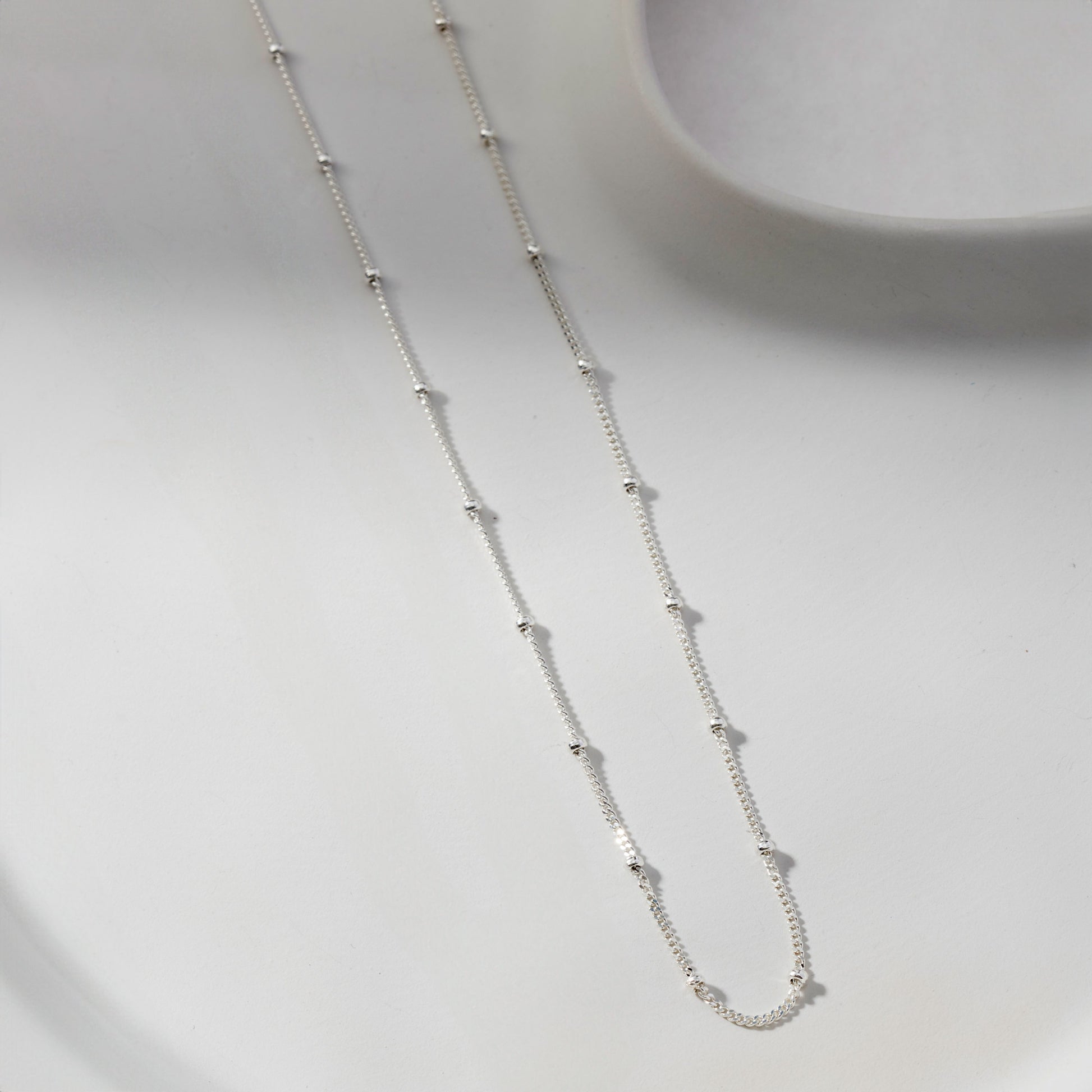 Dainty Bead Chain Necklace Silver with small evenly spaced beads displayed on a white surface.