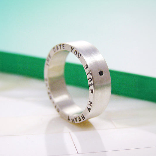 Close-up of chunky silver ring with black diamond and personalised engraving.