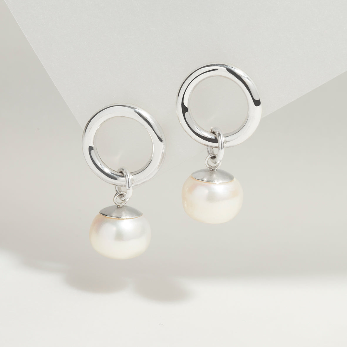 Sterling silver circle stud earrings with freshwater pearl drops, simple and elegant.
