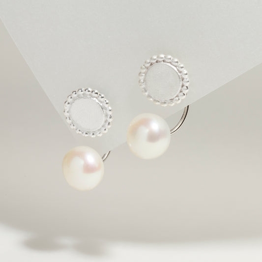 Sterling silver ear jackets with freshwater pearls and a detailed round silver disc with dotted edges.
