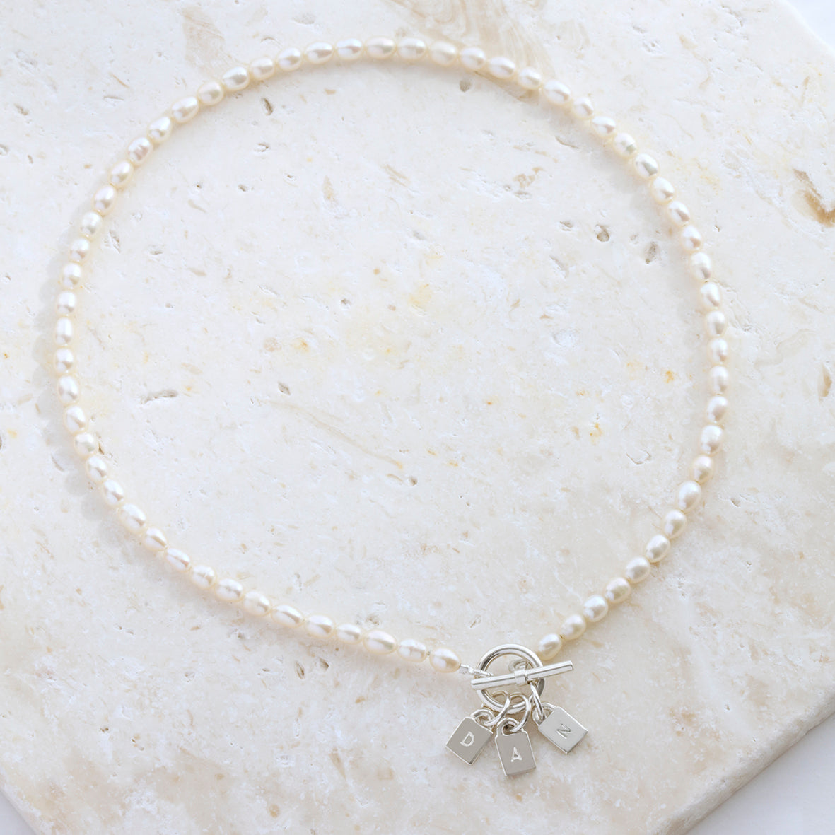 Freshwater pearl necklace with three silver engraved padlock charms personalised with initials.
