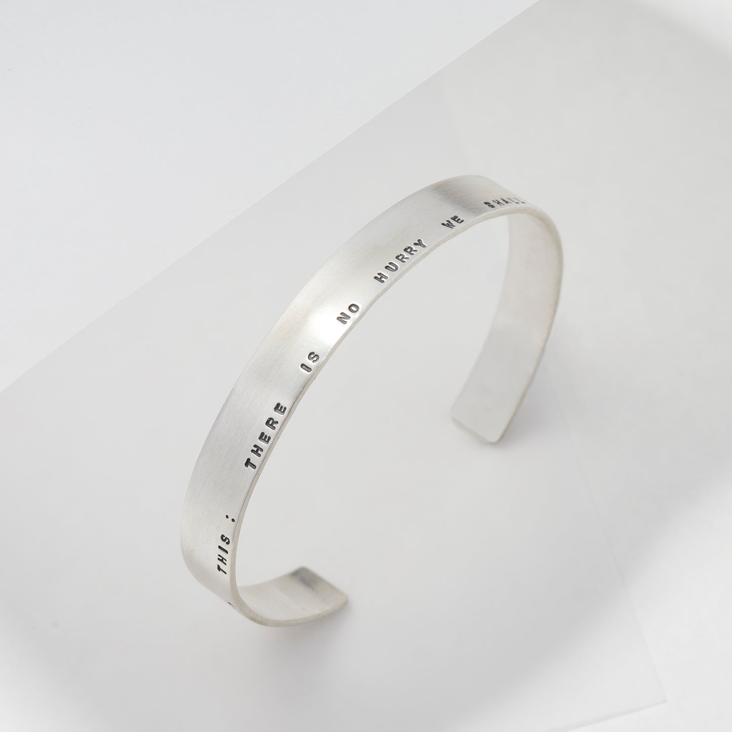 A sleek personalised sterling silver cuff bracelet with a brushed matte finish, engraved with a custom message.