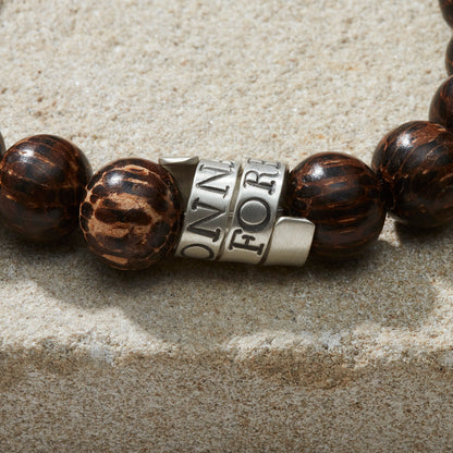 Close up of personalised silver scroll charm on men's wooden round bead bracelet