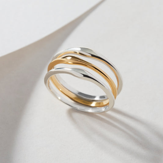 A trio of Slender Ripple Stacking Rings in sterling silver and 18ct gold vermeil, displayed flat on a white surface, highlighting their delicate ripple feature.