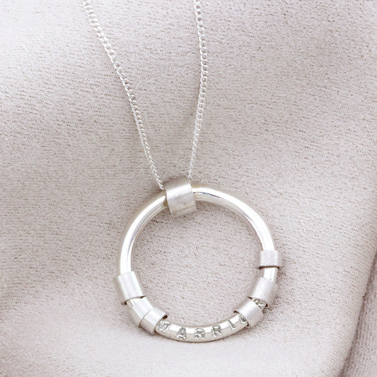 Close-up of sterling silver hidden message necklace with spinning beads around the circle pendant.
