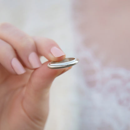 Sterling silver Mobius rings with gemstone detailing in the palm of a hand.
